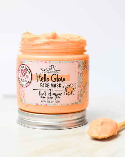 Open jar of Bella and Bear Hello Glow face mask in peach cream with wooden spatula showing texture