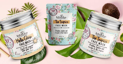 Bella and Bear Hello Glow face mask jar with two The Tropics face mask containers on tropical leaves
