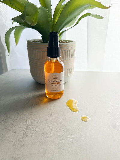 R Drew Naturals Turmeric and lemon facial oil amber pump bottle with spilled drops on tabletop