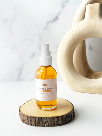 R Drew Naturals LLC Turmeric and lemon facial oil in a clear pump bottle on wood slice display